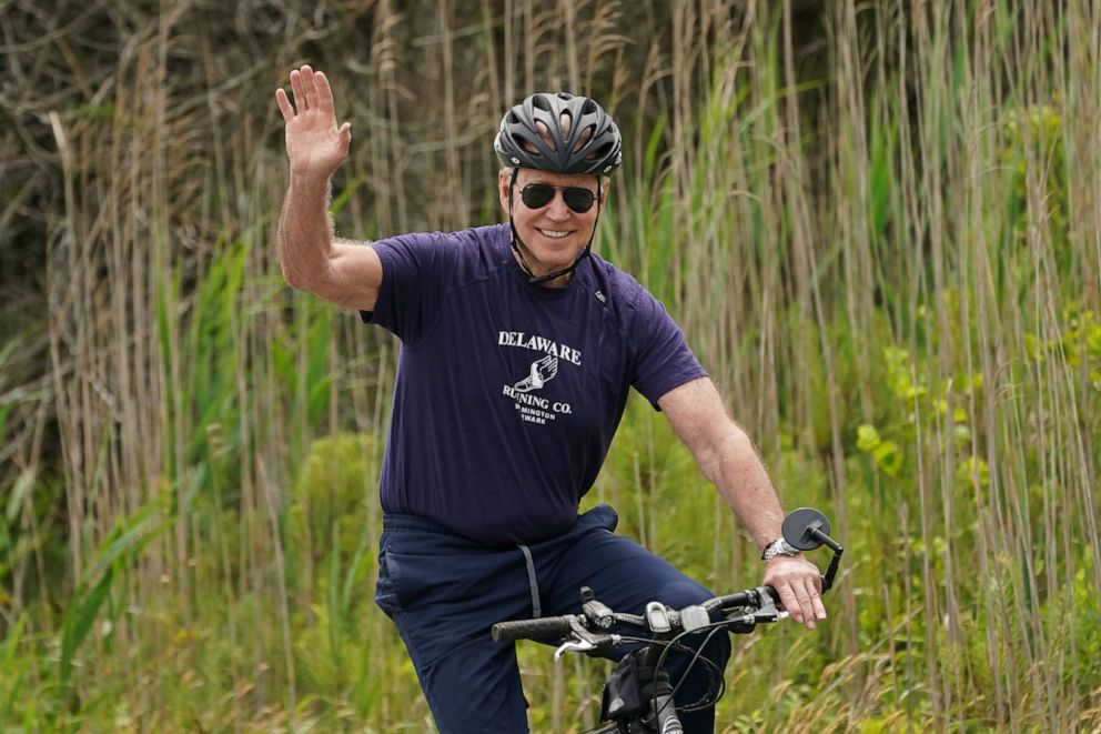 PHOTO: President Joe Biden waves from his bike while riding at Cape Henlopen State Park in Rehoboth Beach, Del., June 3, 2021.