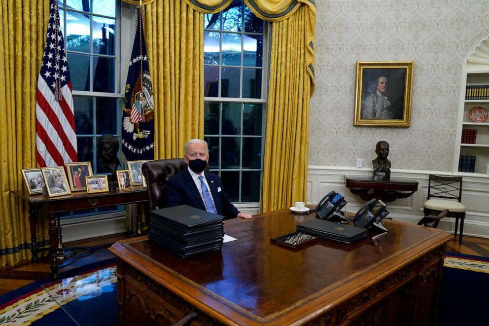 PHOTO: President Joe Biden signs his first executive orders in the Oval Office of the White House, Jan. 20, 2021, in Washington.