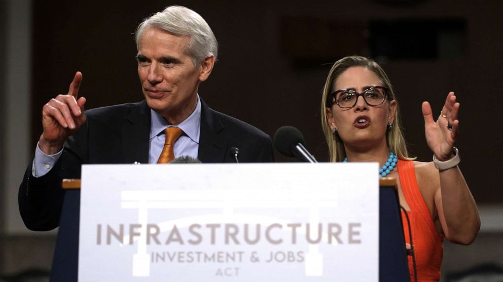 PHOTO: *** BESTPIX *** WASHINGTON, DC - JULY 28:  U.S. Sen. Rob Portman (R-OH) (L) and Sen. Kyrsten Sinema (D-AZ) (R) answer questions from members of the press during a news conference after a procedural vote for the bipartisan infrastructure framework.