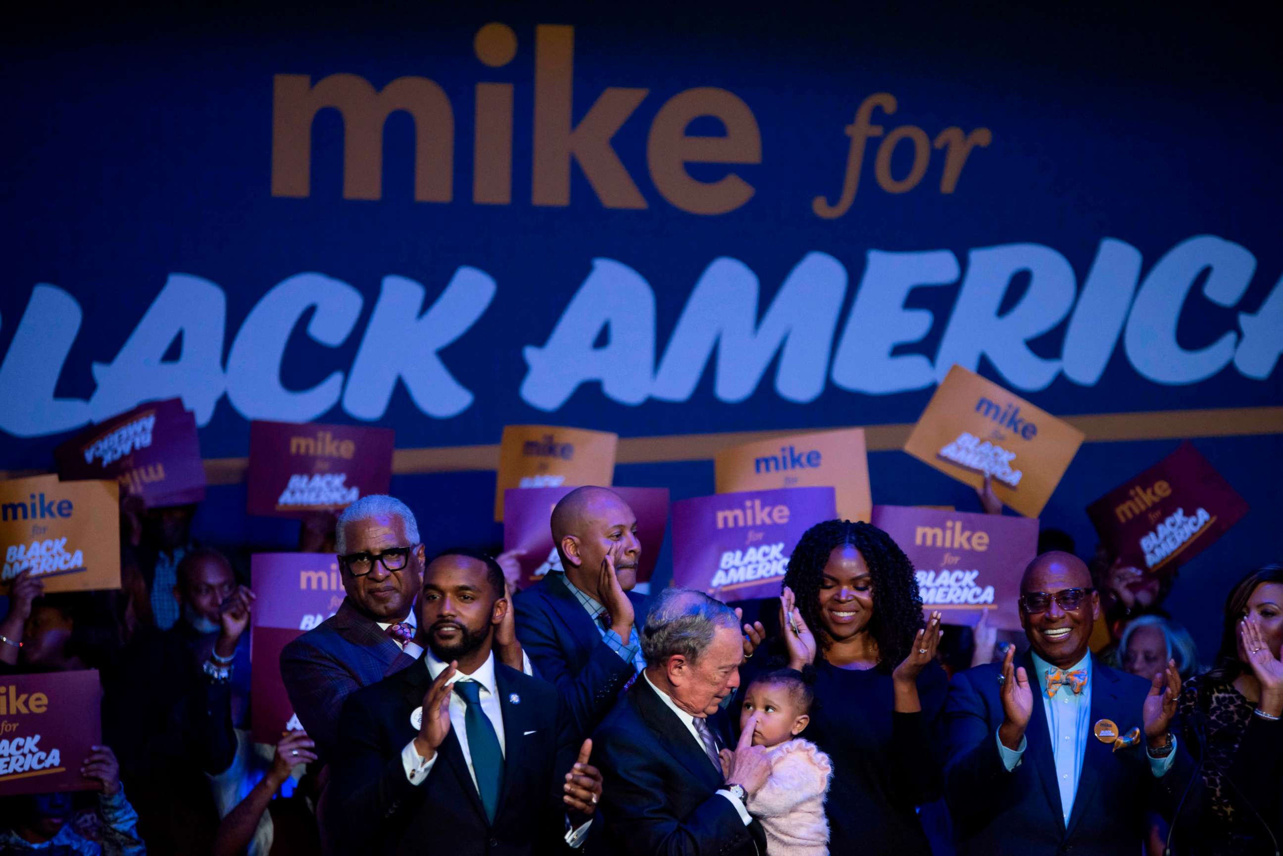 PHOTO: TOPSHOT - Democratic presidential hopeful Mike Bloomberg (C) holds a baby during the "Mike for Black America Launch Celebration" at the Buffalo Soldier National Museum in Houston, Texas, on February 13, 2020. 