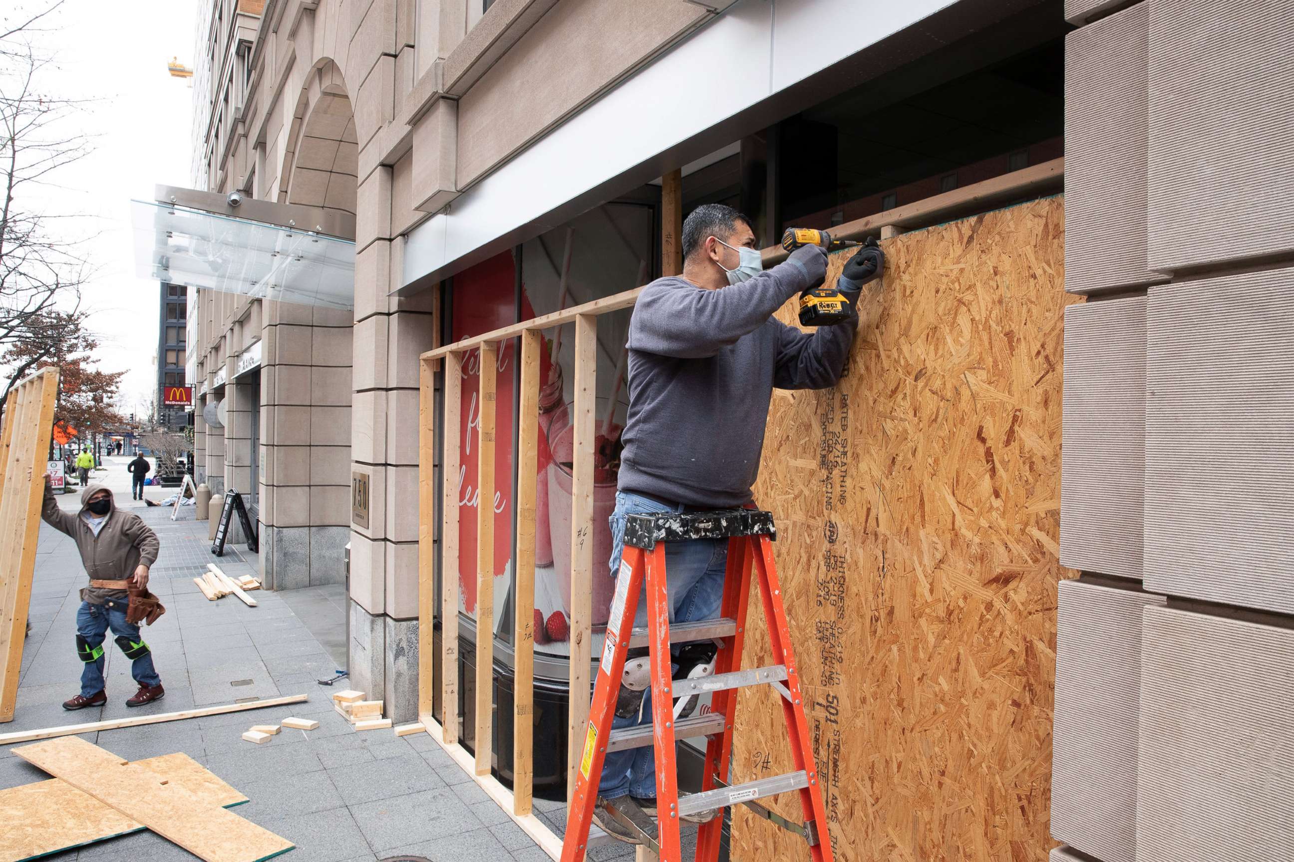 PHOTO: Workers place wood panels to reinforce window panes on a commercial building ahead of anticipated pro-Trump protests, in Washington, D.C., Jan. 4, 2021