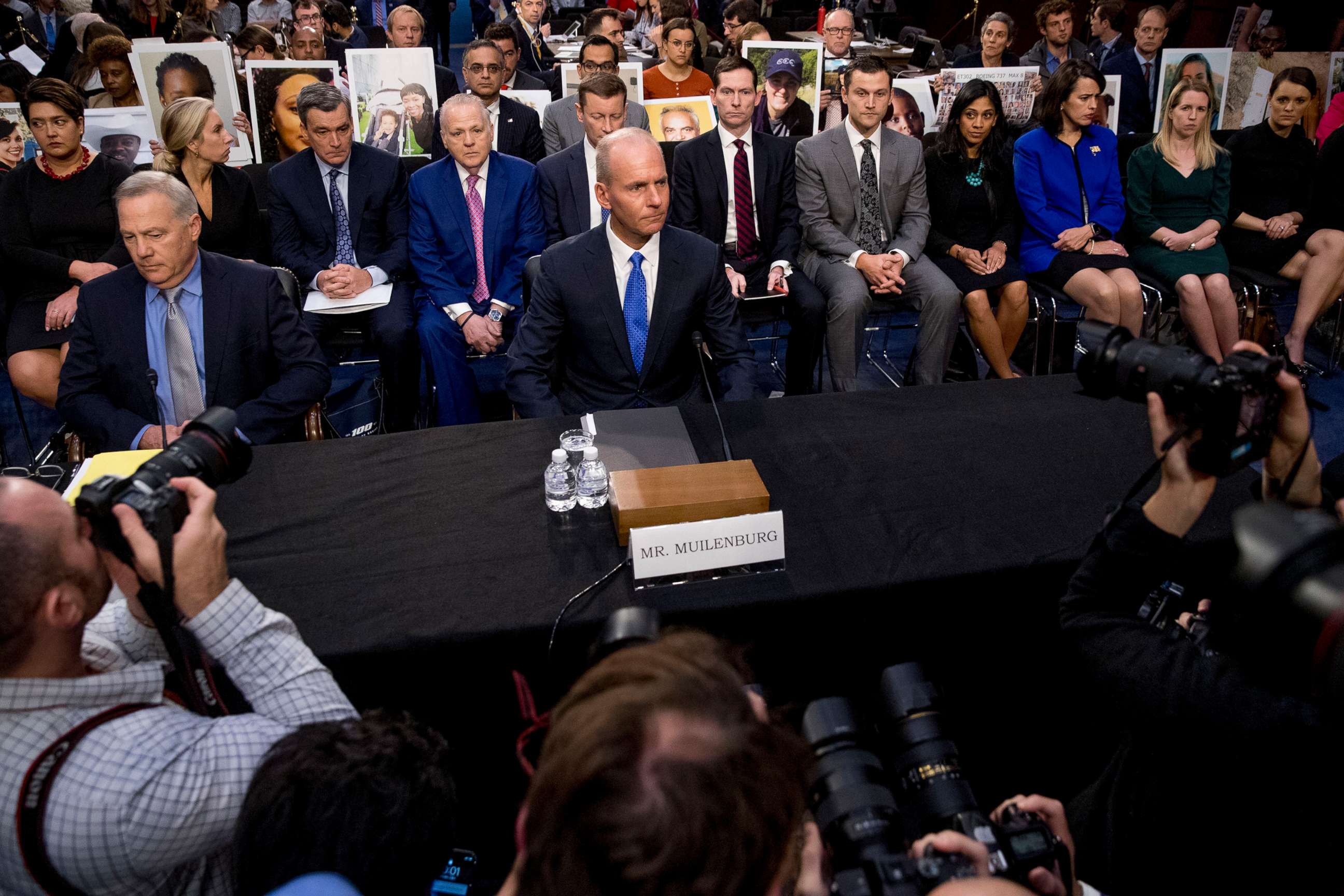 PHOTO: Survivors of those killed in the Ethiopian Airlines Flight 302 and Lion Air Flight 610 crashes hold photos of their family members behind  Dennis Muilenburg, center, and John Hamilton, left, on Capitol Hill in Washington, Oct. 29, 2019.