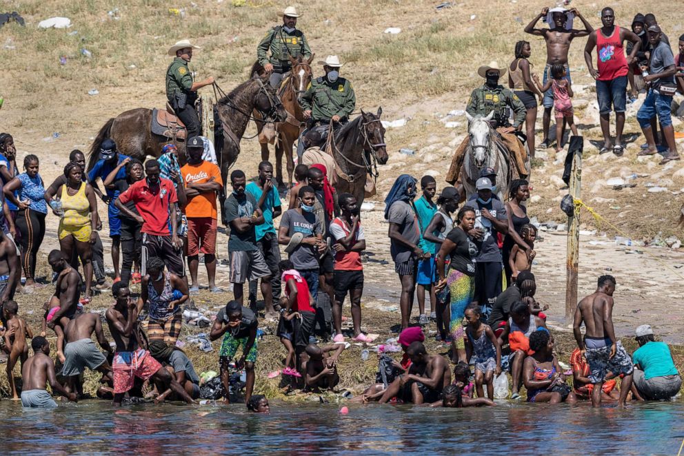 PHOTO: Border Patrol agents watch Haitian immigrants on the bank of the Rio Grande in Del Rio, Texas, Sept. 20, 2021, as seen from Ciudad Acuna, Mexico.