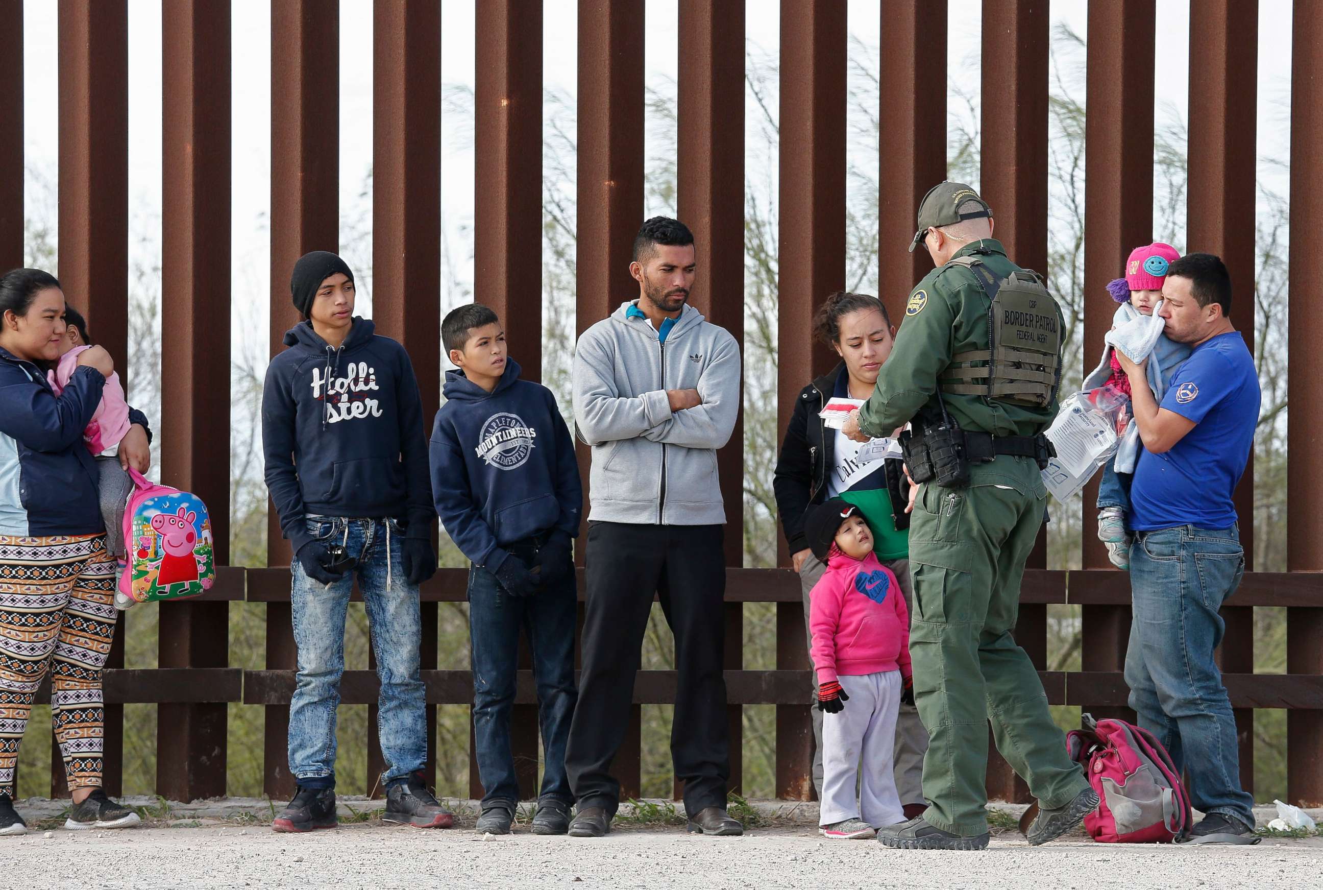 PHOTO: Families that crossed the border to enter the United States illegally turn themselves in to Border Patrol agents next to a fence along the Rio Grande River near McAllen, in Texas, Jan. 23, 2019.