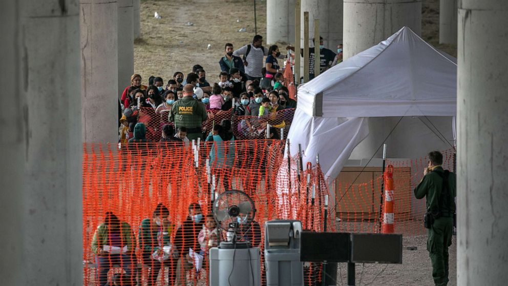 PHOTO: Asylum seekers listen to instructions at an outdoor U.S. Border Patrol processing center under the Anzalduas International Bridge after crossing the Rio Grande from Mexico, March 23, 2021 near Mission, Texas. 