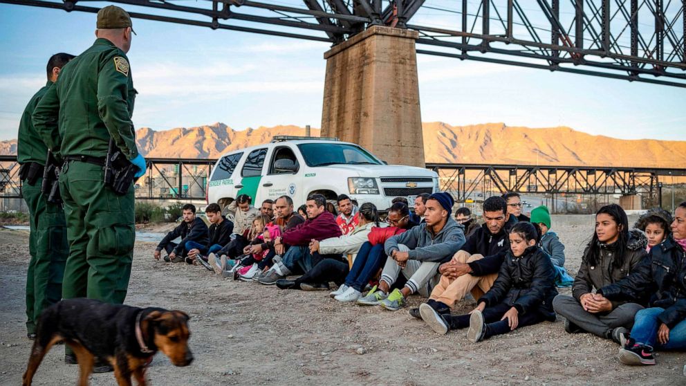 PHOTO: (A group of migrants, who had just crossed the border, sit on the ground near U.S. Border Patrol agents on the US-Mexico border in Sunland Park, N.M., March 20, 2019.