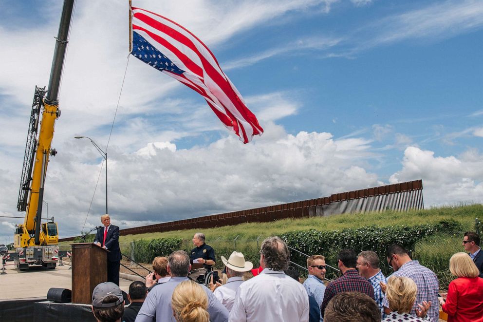 PHOTO: FILE - People listen to former President Donald Trump's address during a tour to an unfinished section of the border wall, June 30, 2021 in Pharr, Texas.