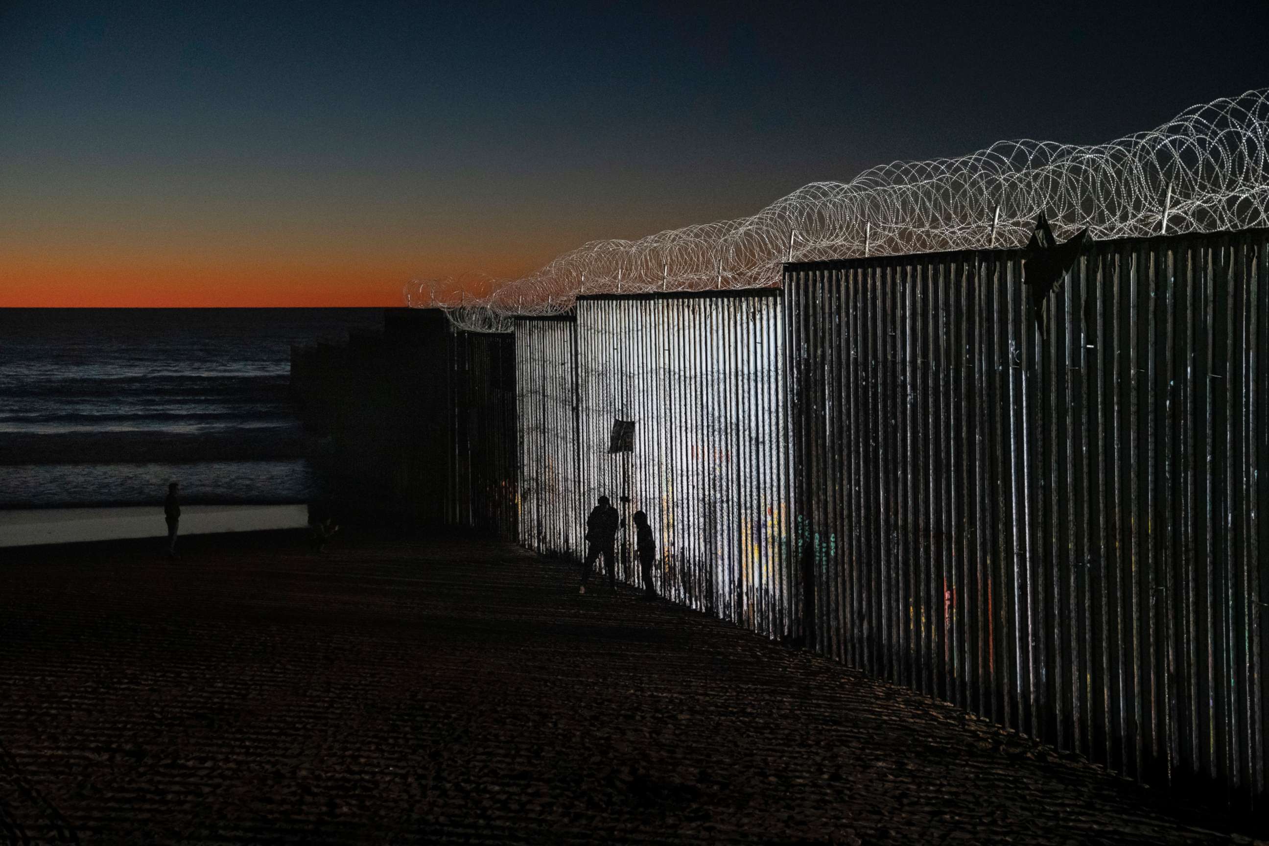 PHOTO: The sun sets while people walk close to the border fence between the U.S. side of San Diego, Calif., and Tijuana, in Mexico, Jan. 2, 2019.