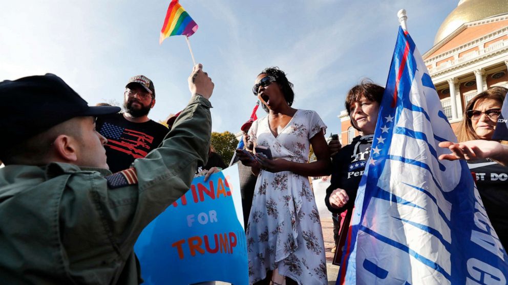 PHOTO: A supporter of President-elect Joe Biden, left, holds a rainbow flag in front of supporters of President Donald Trump outside the Statehouse, Nov. 7, 2020, in Boston.