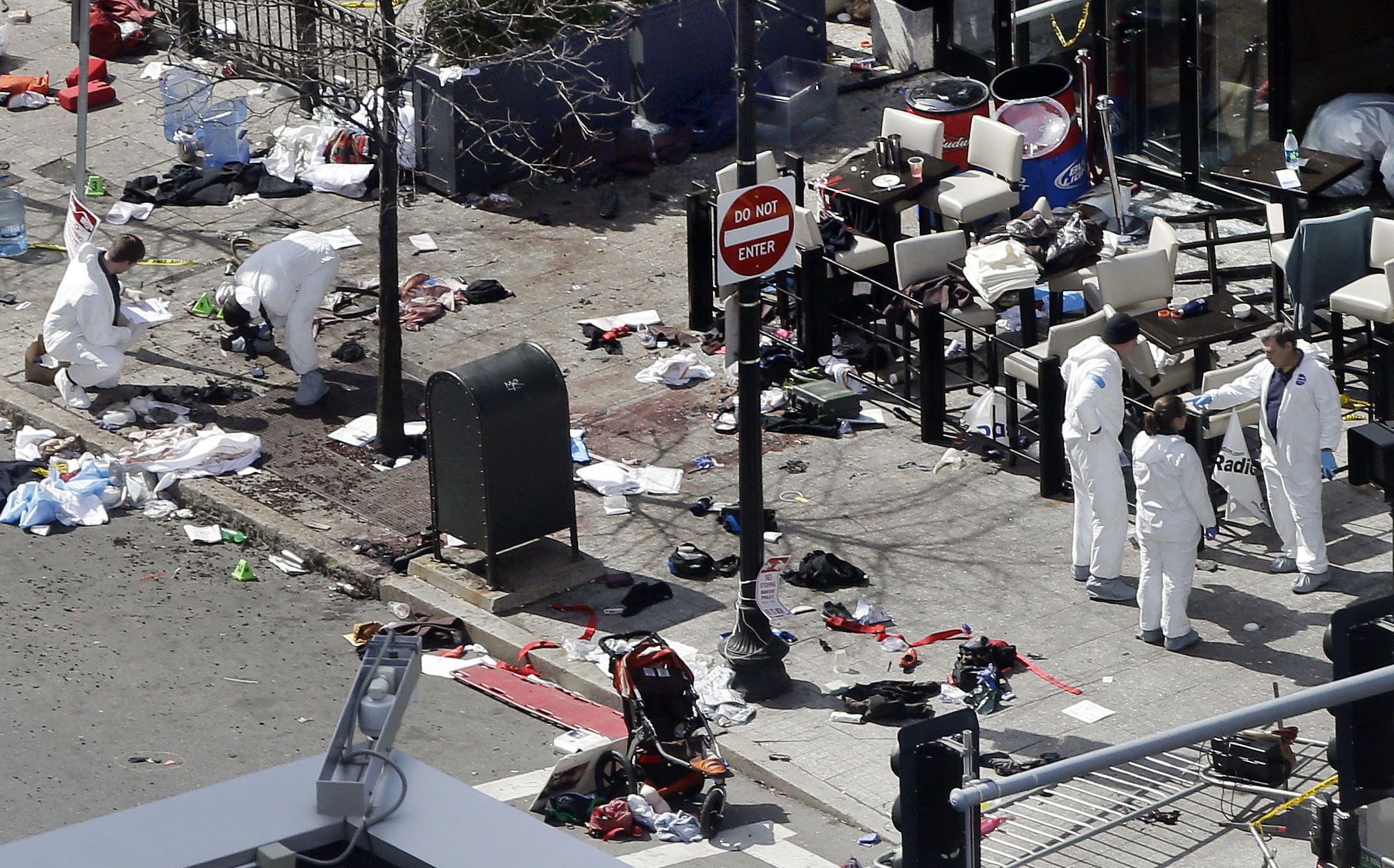 PHOTO: Investigators examine the scene of the second bombing outside the Forum Restaurant on Boylston Street near the finish line of the 2013 Boston Marathon.