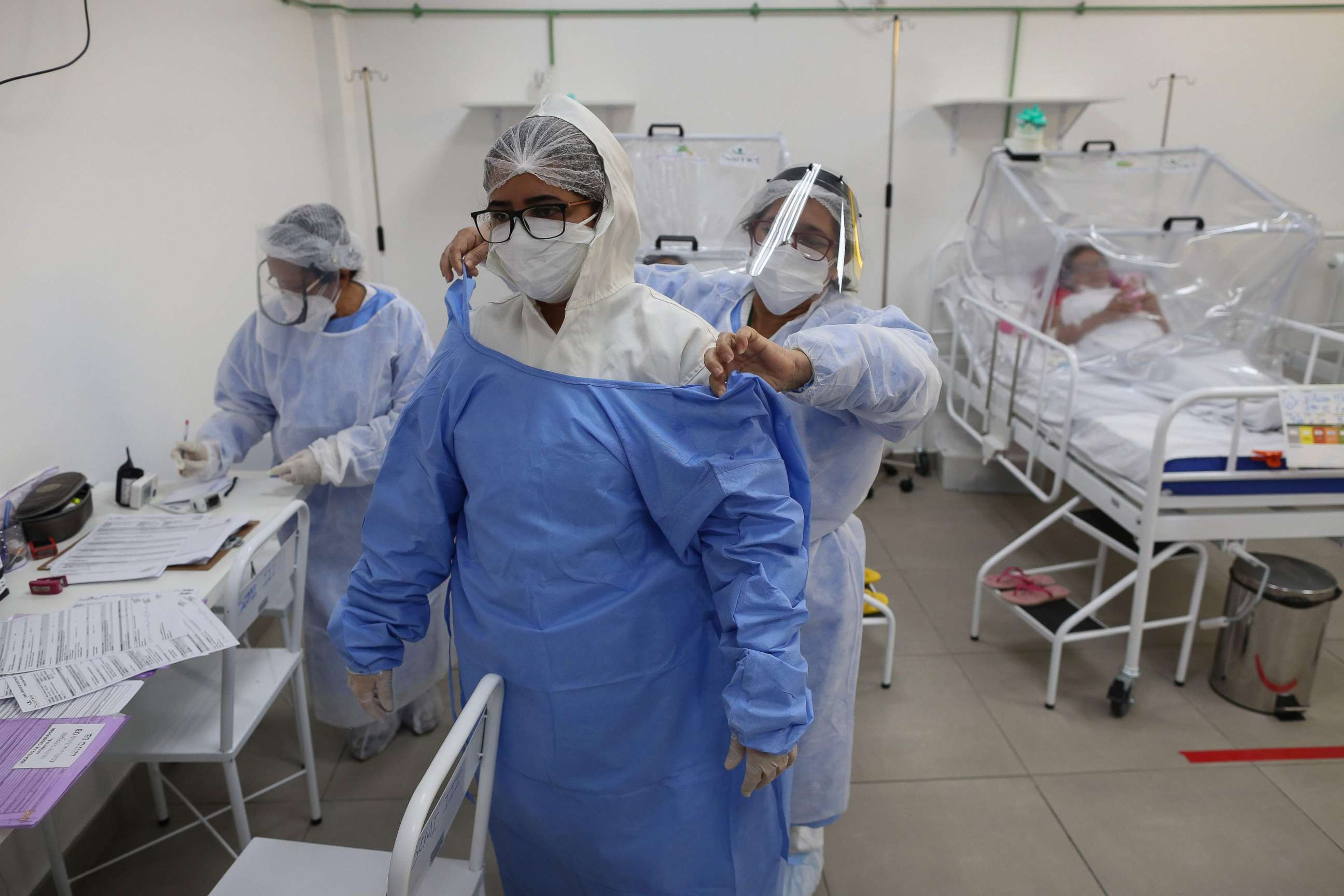 PHOTO: A health worker helps a woman put on protective gear at the Intensive Care Unit for COVID-19 of the Gilberto Novaes Hospital in Manaus, Brazil, May 20, 2020. 