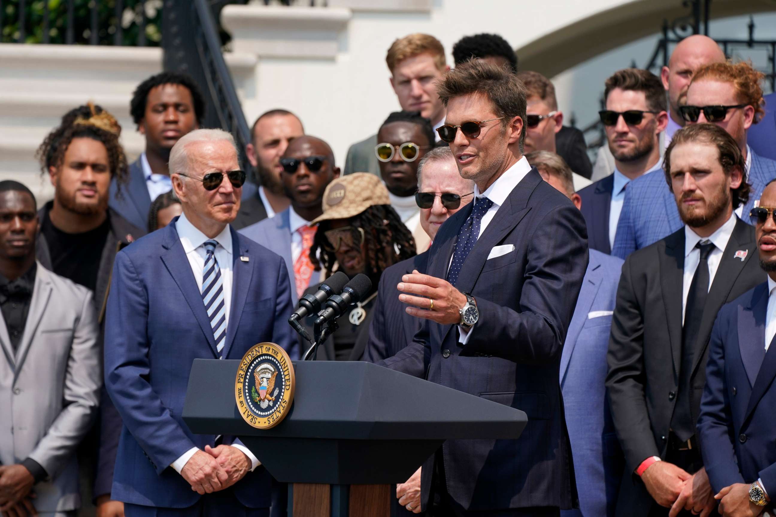 PHOTO: President Joe Biden, surrounded by members of the Tampa Bay Buccaneers, listens as Tampa Bay Buccaneers quarterback Tom Brady speaks during a ceremony on the South Lawn of the White House, in Washington, July 20, 2021