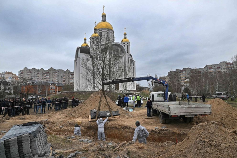 PHOTO: Journalists gather as bodies are exhumed from a mass-grave in the grounds of the St. Andrew and Pyervozvannoho All Saints church in the town of Bucha, northwest of Kyiv, Urkaine, on April 13, 2022.