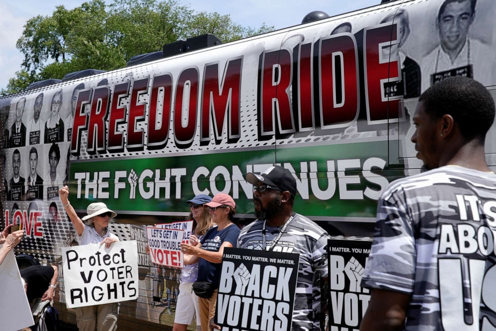 PHOTO: People display signs in front of a Freedom Ride for Voting Rights 2021 bus before the start of a rally in support of District of Columbia (DC) statehood and voting rights on the National Mall in Washington, D.C., June 26, 2021. 