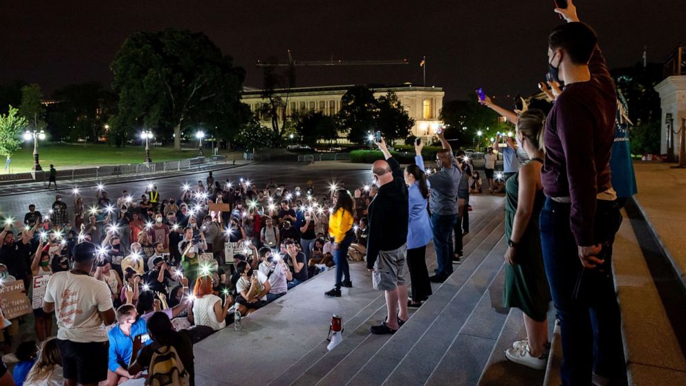PHOTO: Protesters at a midnight rally on the steps of the Capitol hold their phones in the air with Congresswoman Cori Bush, in yellow, in a moment of silence to remember those who have been lost due to homelessness and the pandemic.