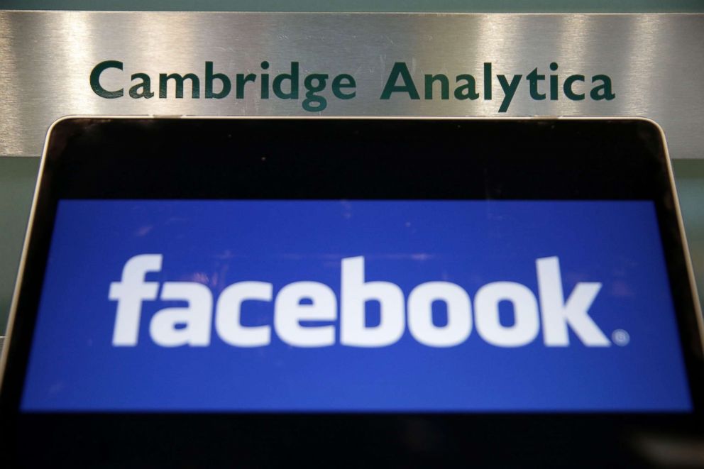 PHOTO: A laptop showing the Facebook logo is held alongside a Cambridge Analytica sign at the entrance to the building housing the offices of Cambridge Analytica, in central London, March 21, 2018.