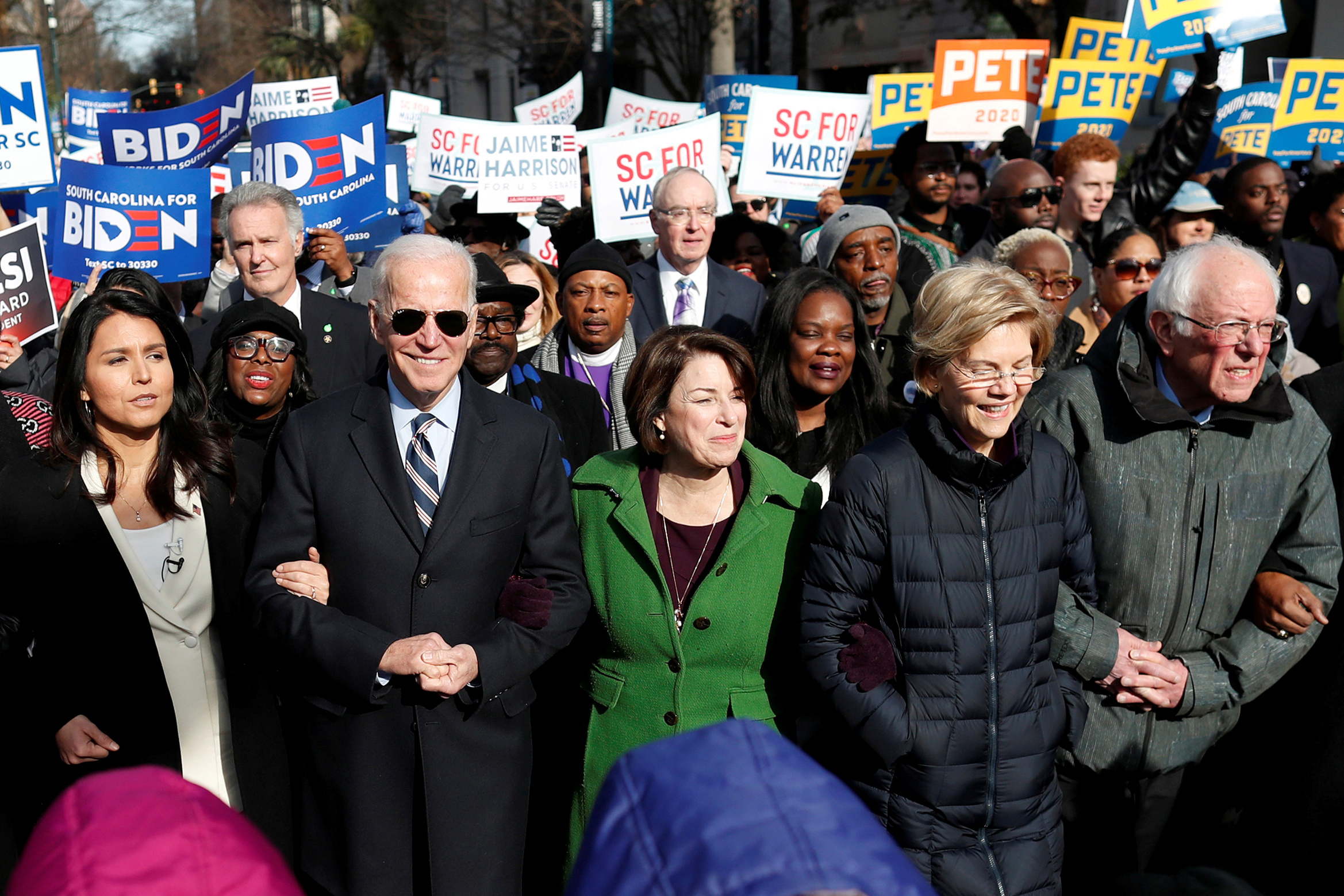 PHOTO: 2020 presidential candidates walk arm-in-arm with local African-American leaders during the Martin Luther King Jr. Day Parade in Columbia, South Carolina, Jan. 20, 2020.