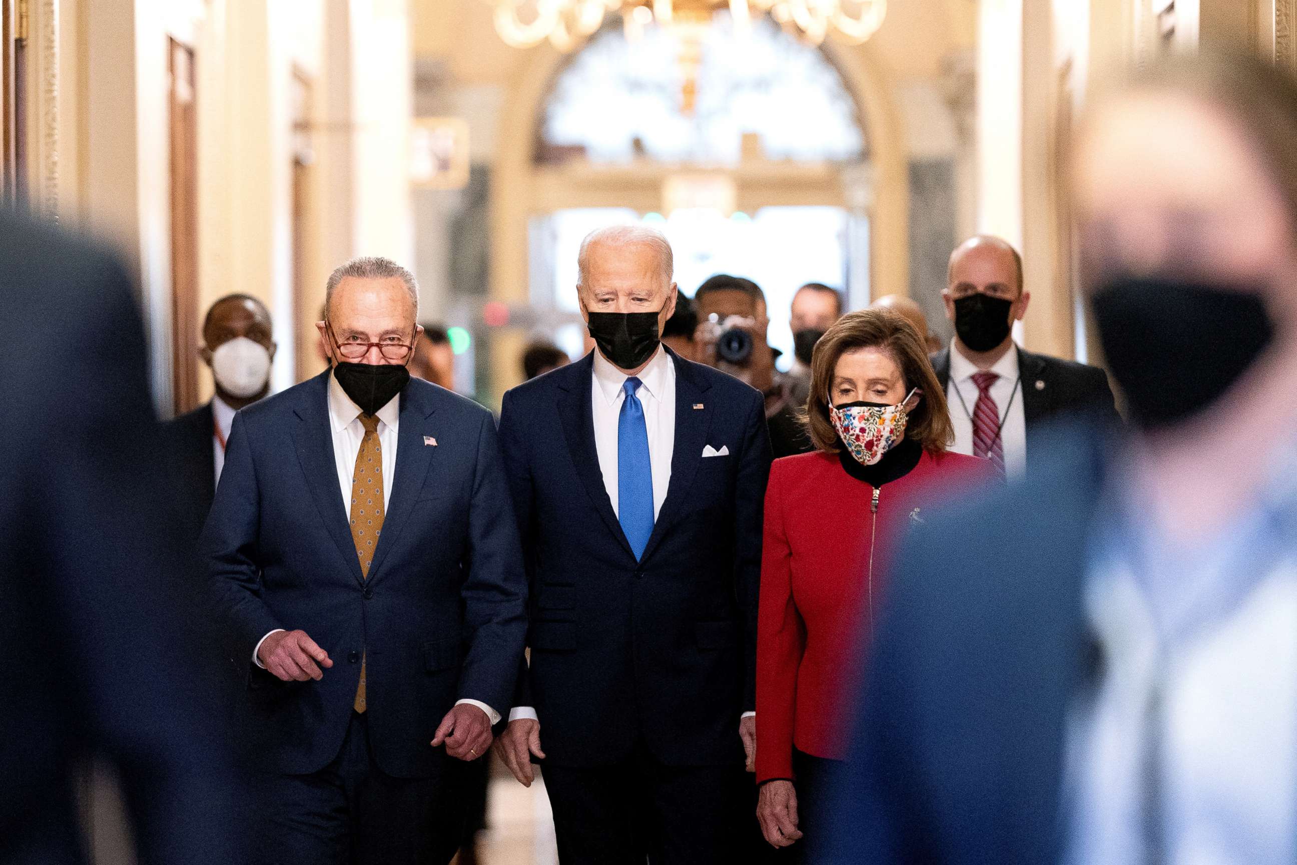 PHOTO: President Joe Biden joined by Senate Majority Leader Chuck Schumer and House Speaker Nancy Pelosi walk through the Hall of Columns before speaking during a ceremony on the first anniversary of the January 6 attack in, Jan. 6, 2022. 