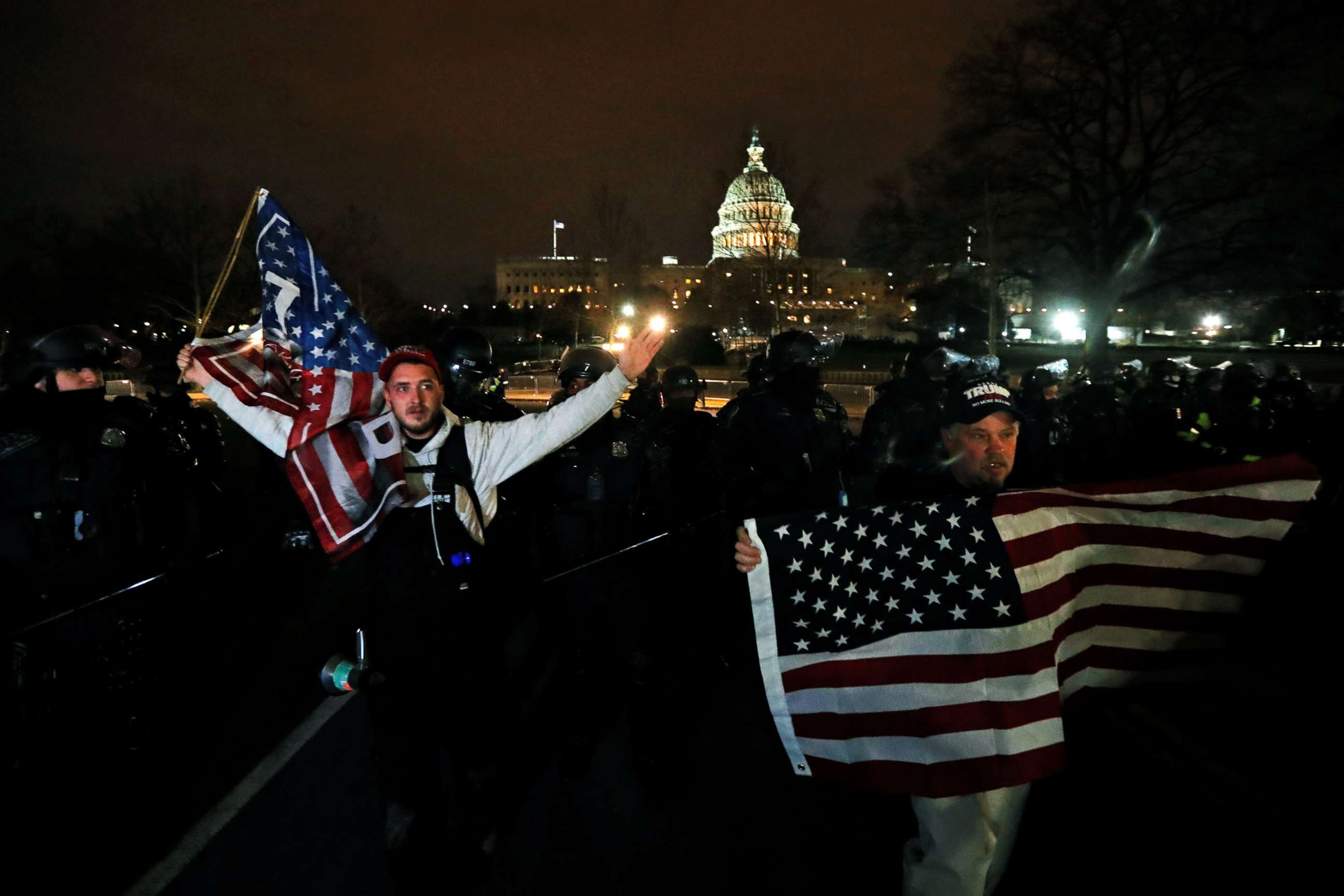 PHOTO: Supporters of President Donald Trump hold U.S. flags as they walk next to police near the Capitol during a protest against the certification of the 2020 U.S. presidential election results by the congress, Jan. 6, 2021.