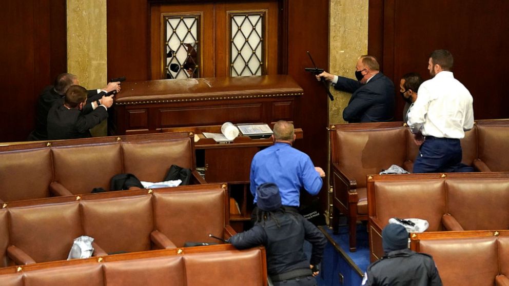 PHOTO: Law enforcement officers point their guns at a door that was vandalized in the House Chamber during a joint session of Congress on Jan. 06, 2021, in Washington.