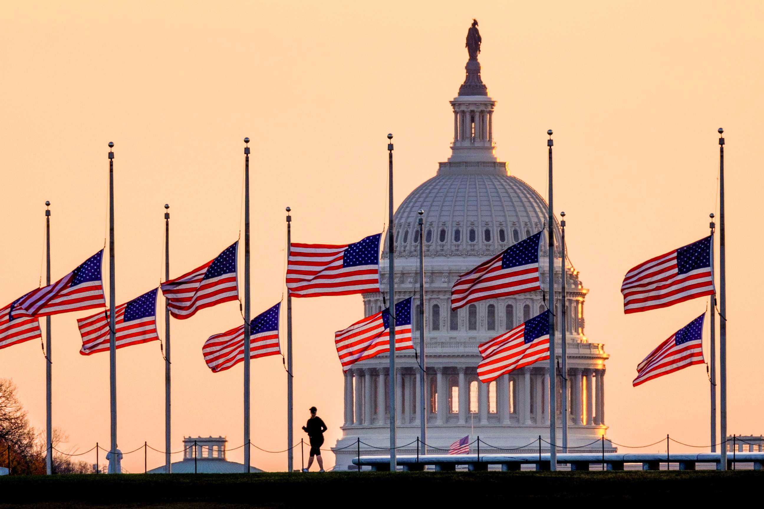 PHOTO: Lowered to half-staff in honor of former Senate Majority Leader Bob Dole of Kansas, flags fly in the breeze at sunrise on the National Mall with the U.S. Capitol in the background, Dec. 6, 2021, in Washington.