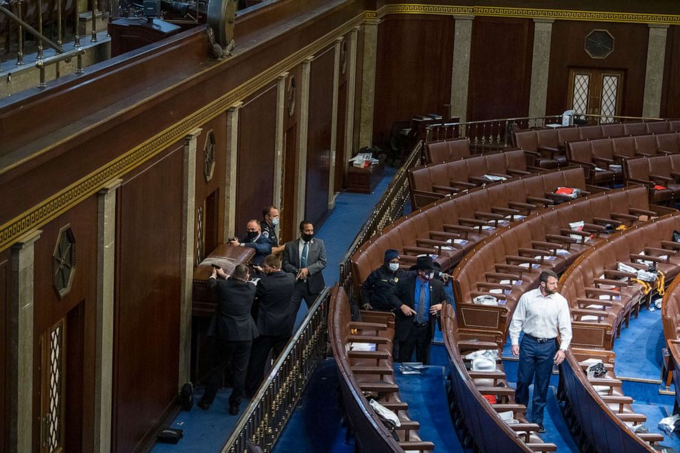 PHOTO: Reps. Markwayne Mullin, right, and Troy Nehls, center, are directed off the floor as security barricades the door of the House chamber from rioters who disrupted the joint session of Congress to certify the Electoral College vote, Jan. 6, 2021. 