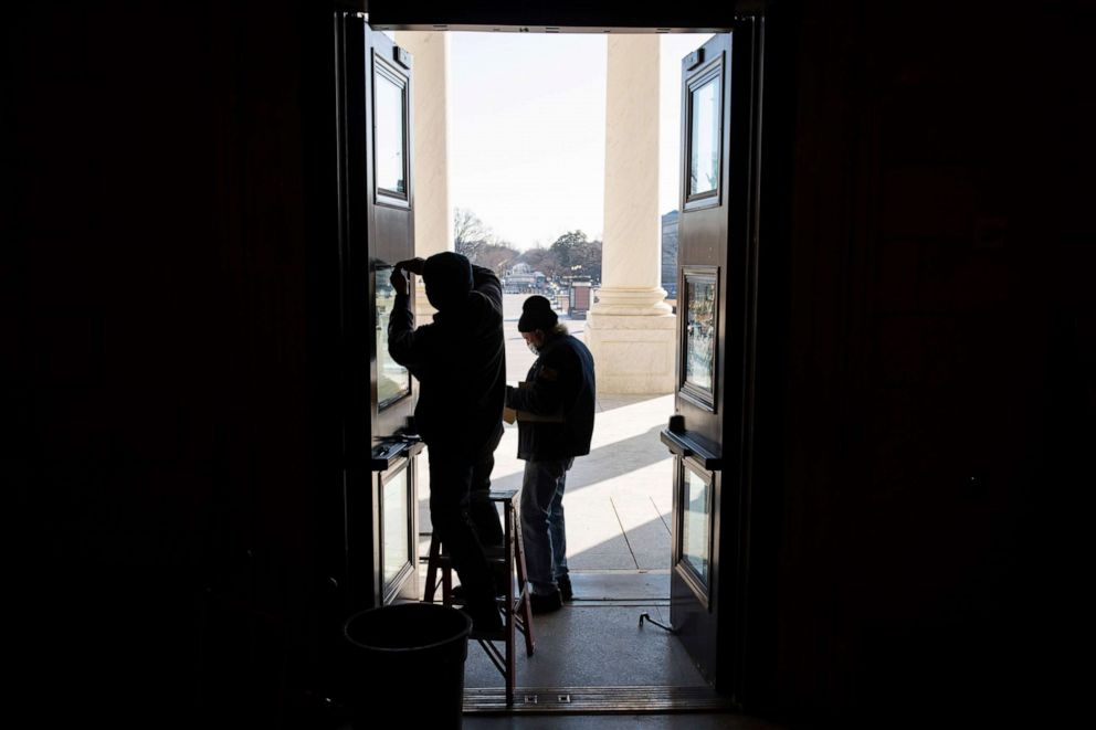 PHOTO: Workers repair panes of glass on the Rotunda Doors that were damaged during the January 6 insurrection, at the U.S. Capitol, in Washington, D.C., on Feb. 8, 2021. 
