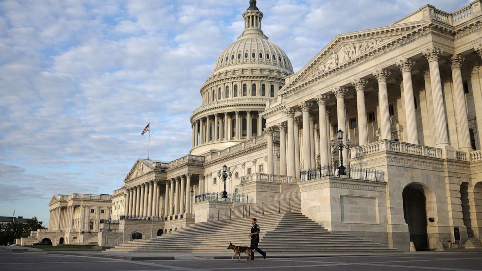PHOTO: A Capitol Police Officer walks a police dog across the west front of the U.S. Capitol Building on May 14, 2021 in Washington, D.C.