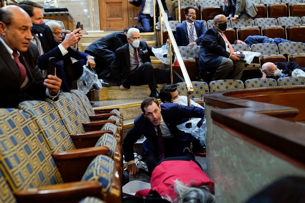 PHOTO: Members of Congress (Rep. Jason Crow D-Colo. at center) shelter in the House gallery as rioters try to break into the House Chamber at the U.S. Capitol on Jan. 6, 2021, in Washington.