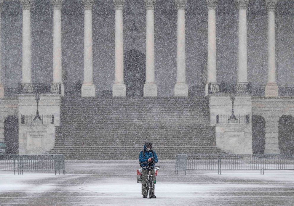 PHOTO: A man takes a break on his bike near the steps of the US Capitol as a snow storm develops in Washington, D.C. on Dec. 16, 2020.