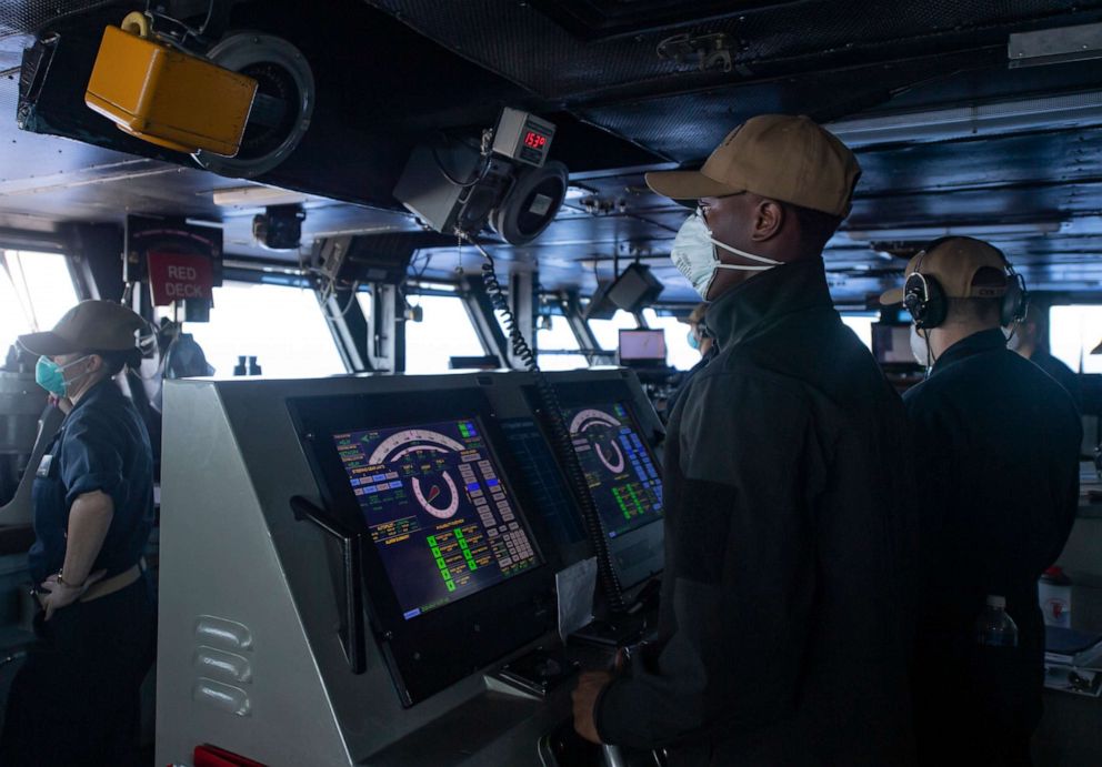 PHOTO: Seaman Cameron Davis mans the helm of the aircraft carrier USS Theodore Roosevelt (CVN 71) as the ship operates in the Philippine Sea, May 21, 2020, following an extended visit to Guam in the midst of the COVID-19 global pandemic.