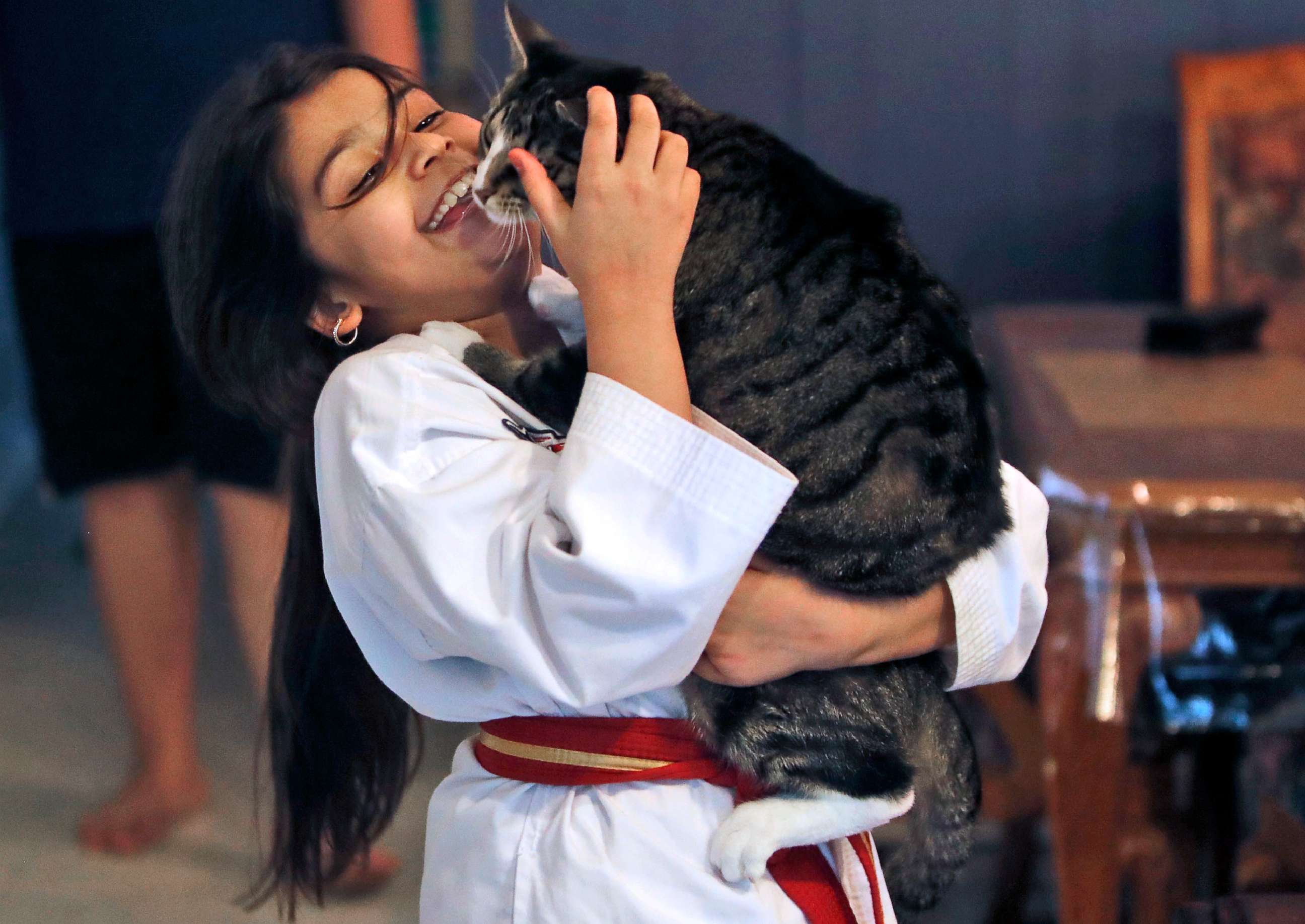 PHOTO: Arfa Yousuf, 8, holds he pet cat after completing her martial arts virtural belt test at her home in Richardson, Texas, April 23, 2020.