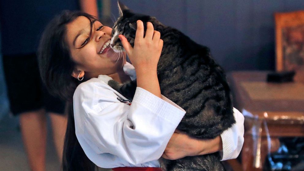 PHOTO: Arfa Yousuf, 8, holds he pet cat after completing her martial arts virtural belt test at her home in Richardson, Texas, April 23, 2020.