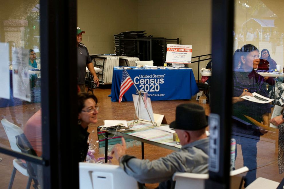 PHOTO: FILE - In this Feb. 8, 2020, file photo, people volunteer to get people registered to vote and a booth offering employment for the upcoming 2020 census stands in the background in Guadalupe, Ariz. 