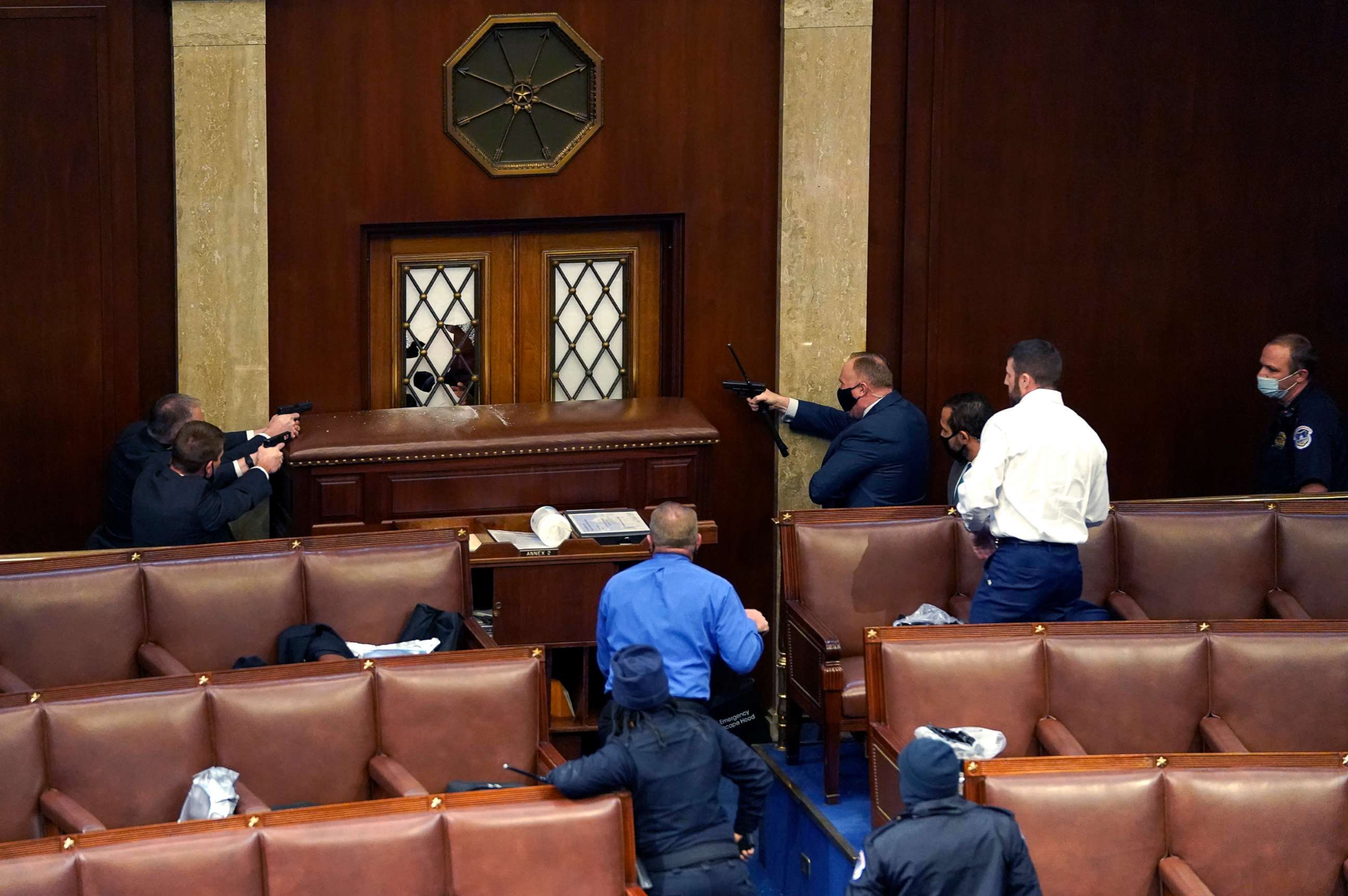 PHOTO: Law enforcement officers point their guns at a door that was vandalized in the House Chamber during a joint session of Congress on Jan. 6, 2021, in Washington, D.C. 