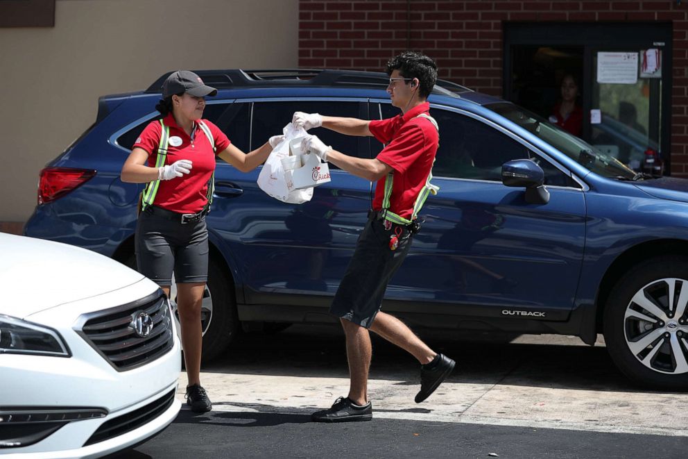 PHOTO: Workers at a Chick-fil-A deliver meals to customers in their vehicles at the drive-up window during the coronavirus pandemic on March 20, 2020, in Pembroke Pines, Fla.