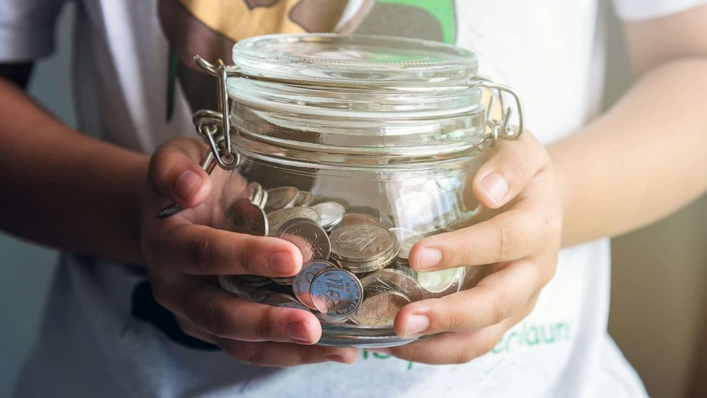 PHOTO: A money jar is held in the hands of a child.