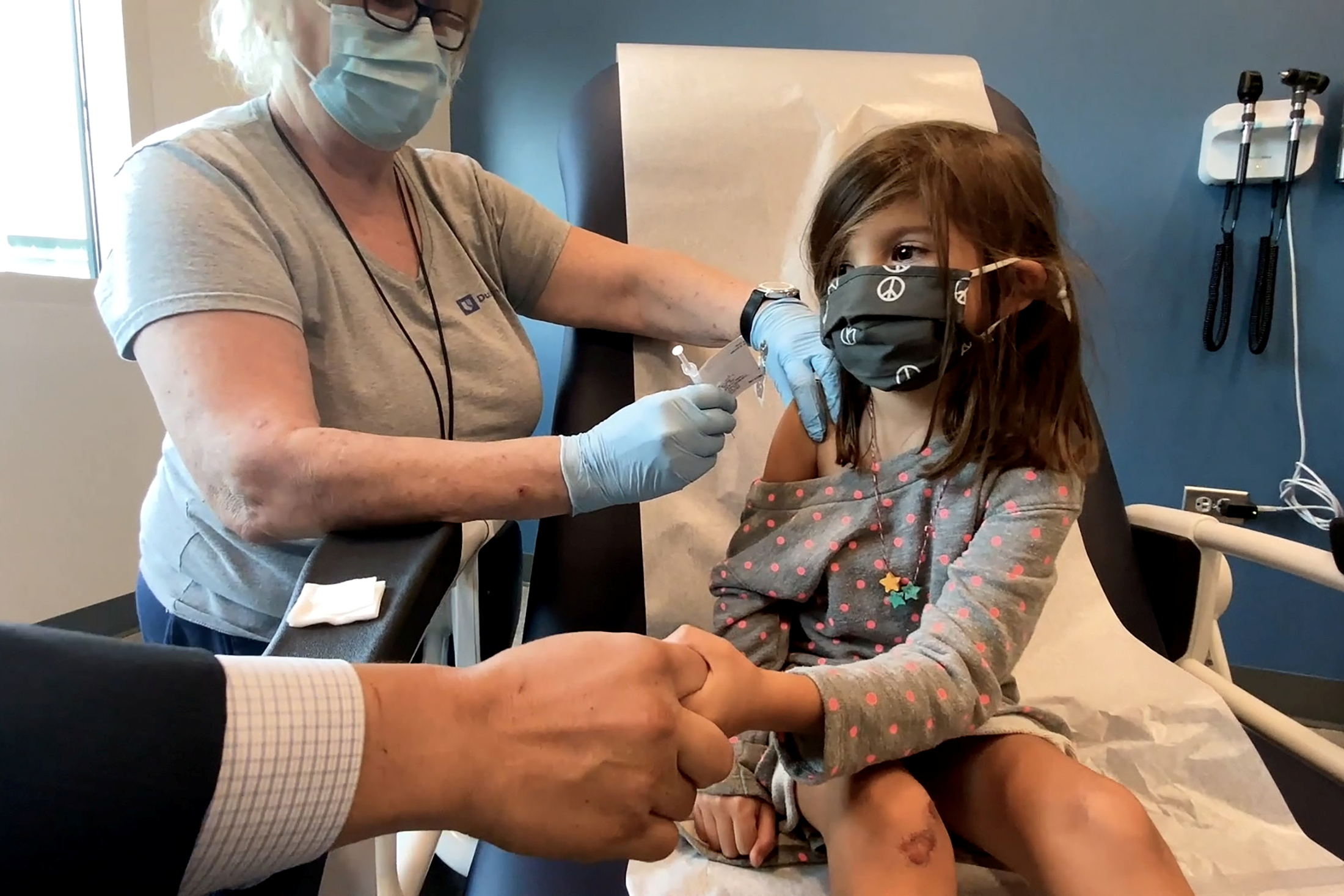 PHOTO: Bridgette Melo, 5, holds the hand of her father, Jim Melo, during her inoculation of one of two reduced doses of the Pfizer COVID-19 vaccine during a trial at Duke University in Durham, N.C., Sept. 28, 2021.