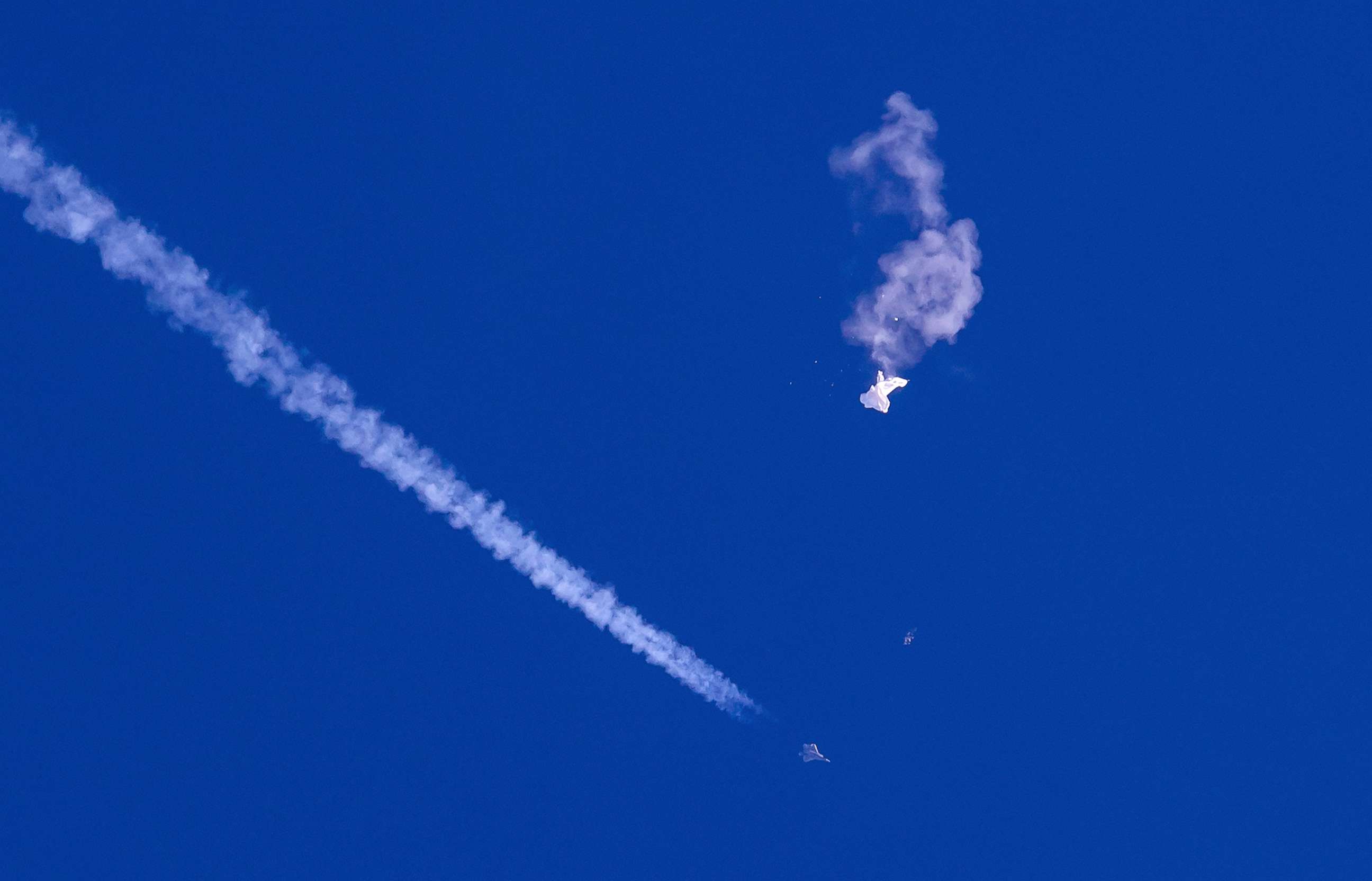 PHOTO: A fighter jet flies past the remnants of a large balloon after it was shot down above the Atlantic Ocean, just off the coast of South Carolina near Myrtle Beach, Feb. 4, 2023.