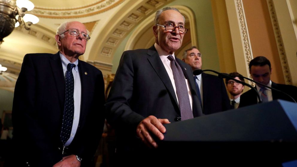 Senate Minority Leader Chuck Schumer, accompanied by Sen. Bernie Sanders and Sen. Jeff Merkley, speaks with reporters following the party luncheons on Capitol Hill in Washington, Oct. 3, 2017. 