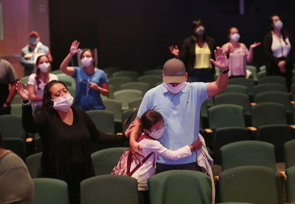 PHOTO: Margaret Cruz, Sophia Perez and Edwin Perez pray together after returning to Potential Church as it opened on May 24, 2020 in Cooper City, Florida.