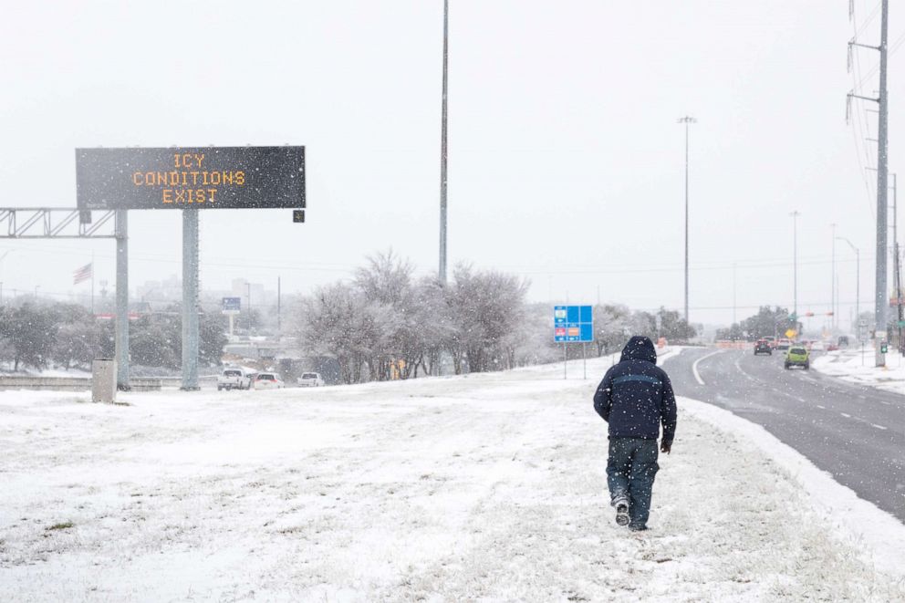 PHOTO: A pedestrians walks past a road sign warning commuters of icy conditions on a road in Austin, Texas, Feb. 18, 2021. 