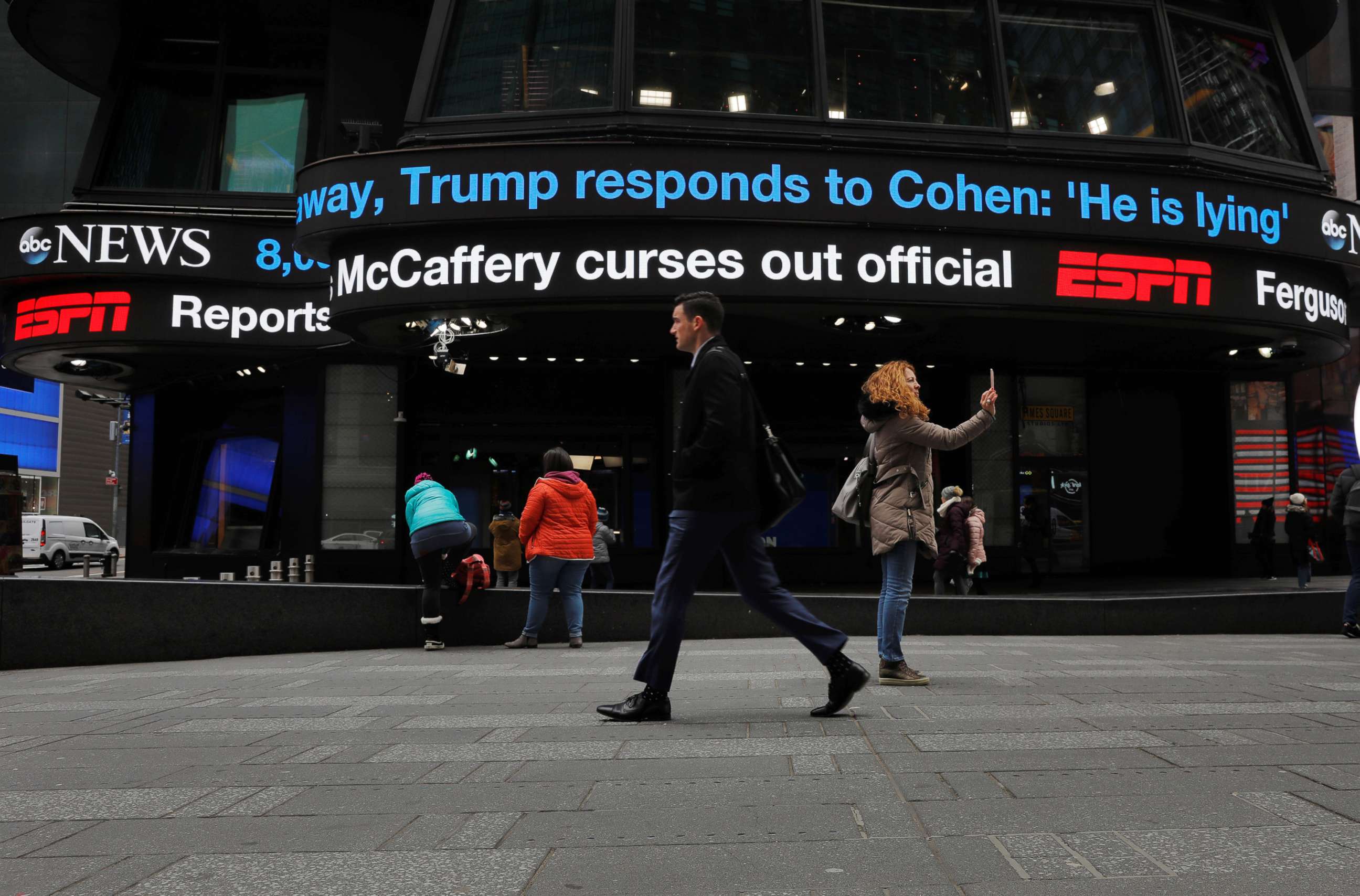 PHOTO: Pedestrians walk past a news banner in the Times Square, New York as it references Michael Cohen, the former personal attorney of President Donald Trump, as he testifies before Congress, Feb. 27, 2019.