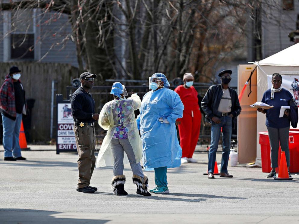 PHOTO: Medical workers talk as people waiting in line to receive testing for COVID-19 outside Roseland Community Hospital, in Chicago, April 7, 2020.