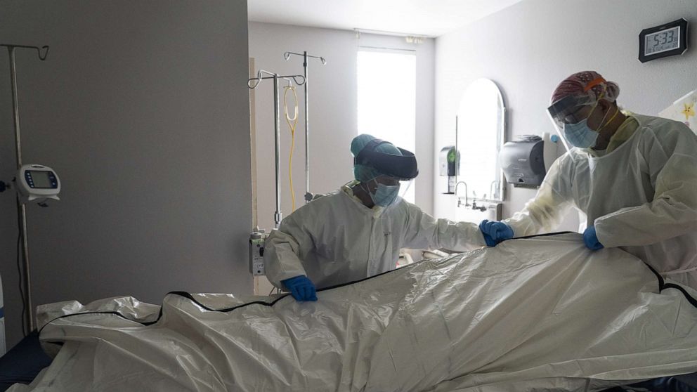 PHOTO: Medical staff wearing full PPE wrap a deceased patient with bed sheets and a body bag in the Covid-19 intensive care unit at the United Memorial Medical Center, June 30, 2020, in Houston.