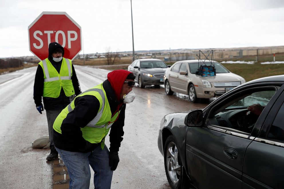 PHOTO: Steve Yankton and Nathaniel Badmilk speak to drivers during a lockdown at the entrance to the Pine Ridge Indian Reservation in Pine Ridge, S.D., April 15, 2020.