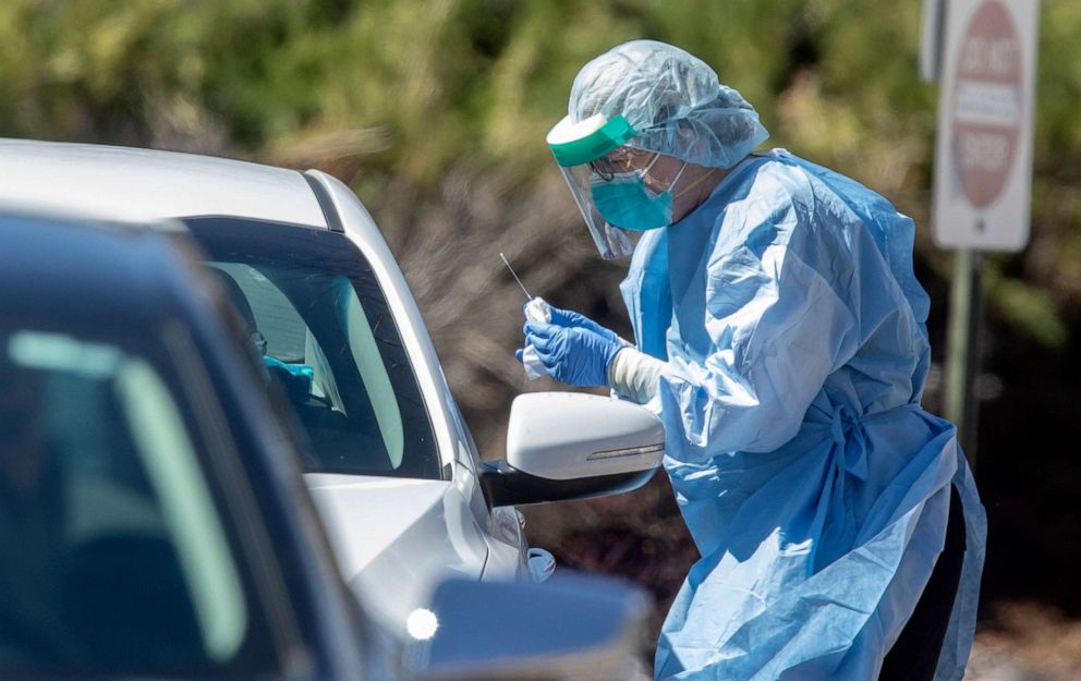 PHOTO: A medical worker administers a test for coronavirus at a drive-up testing center at GraceMed Health Clinic in Wichita, Kan., March 25, 2020. 