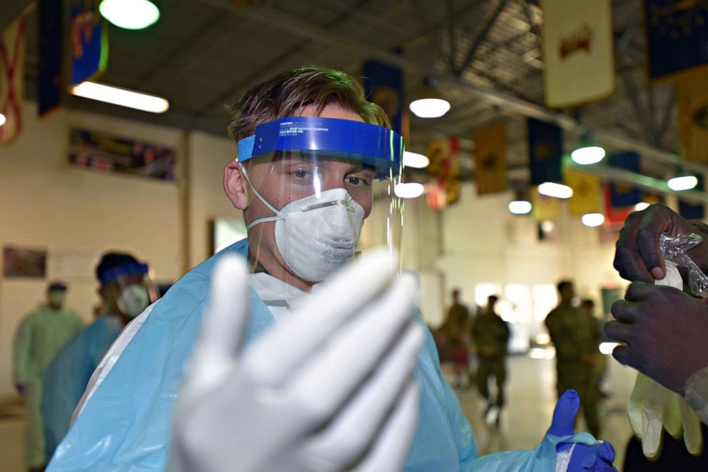 PHOTO: Army Specialist Daulton Radler inspects his glove fit as he is shown the proper procedures for donning personal protective equipment (PPE), in Plymouth Meeting, Pa., April 2, 2020.