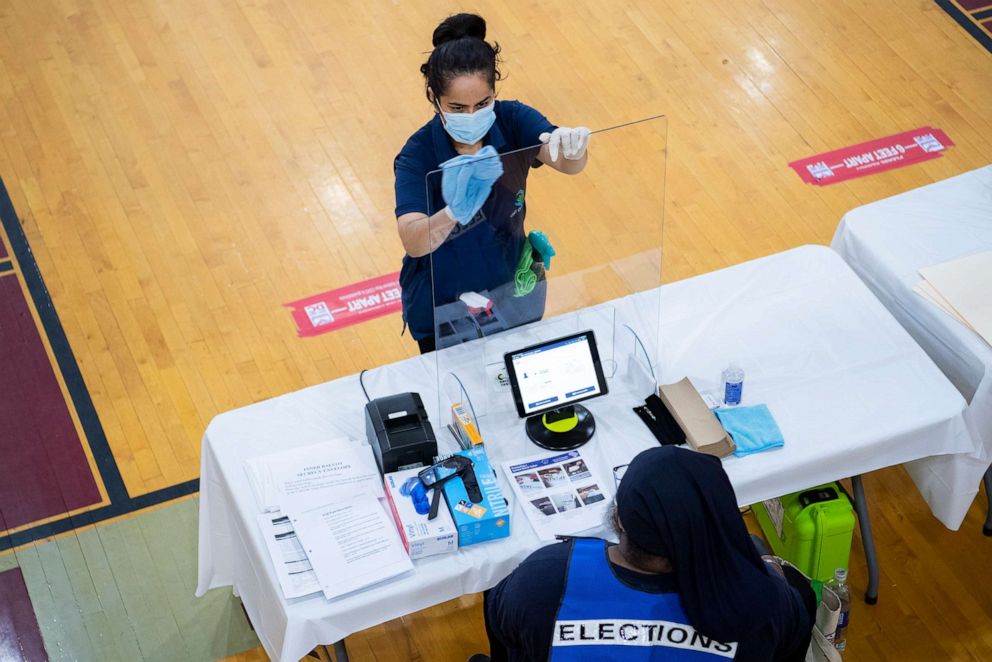 PHOTO: A worker cleans an election officials station during early voting for the June 2nd primary at McKinley Technology High School in Washington, D.C., May 26, 2020. 