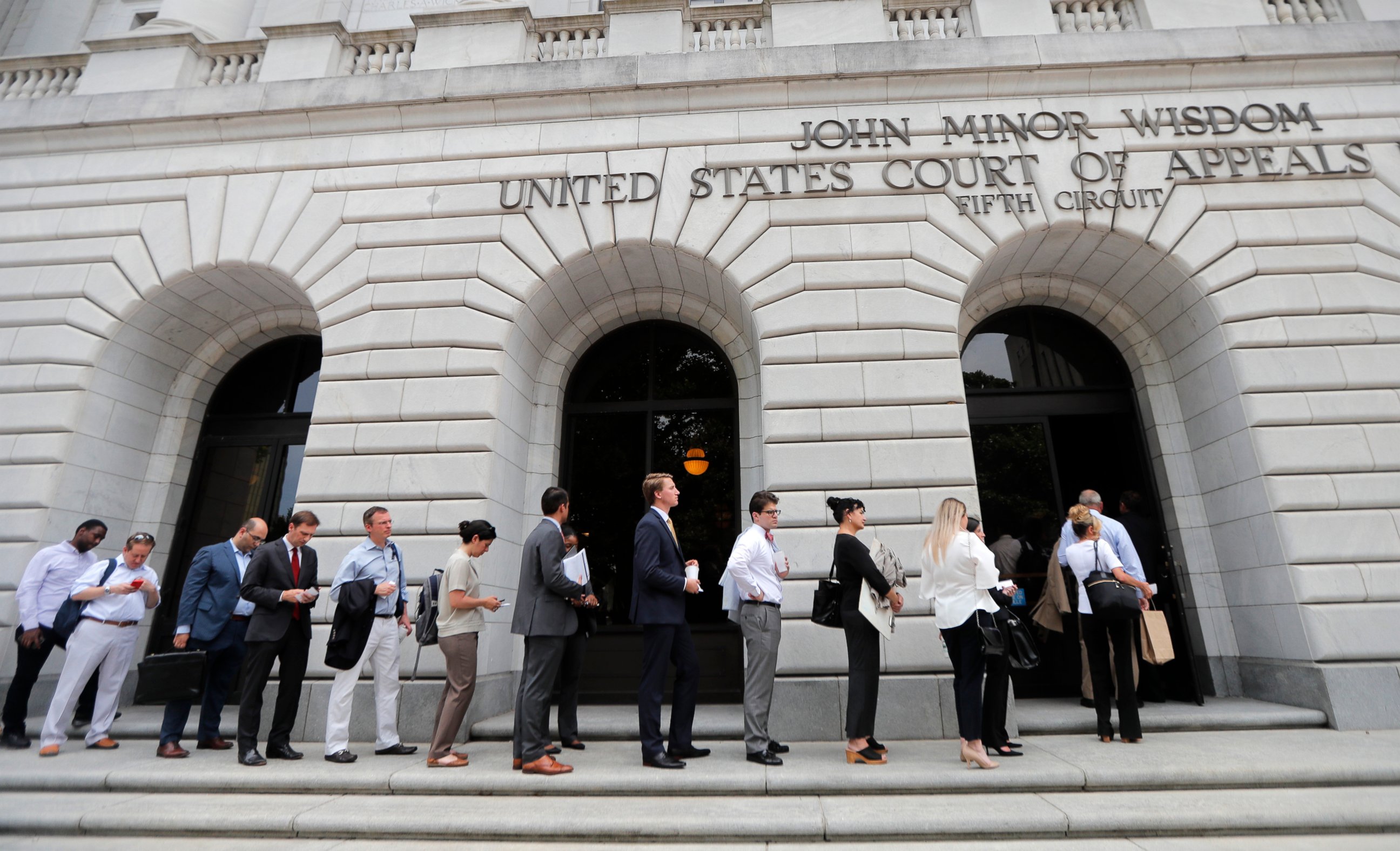 PHOTO: In this Tuesday, July 9, 2019 file photo, People wait in line to enter the 5th Circuit Court of Appeals to sit in overflow rooms to hear arguments in New Orleans.
